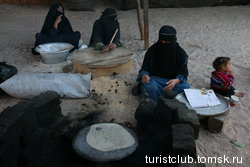 Бедуинки пекут лепешки на металлическом круге.
